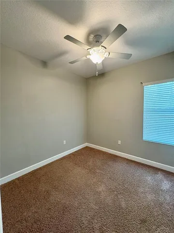 an empty room with a window and ceiling fan