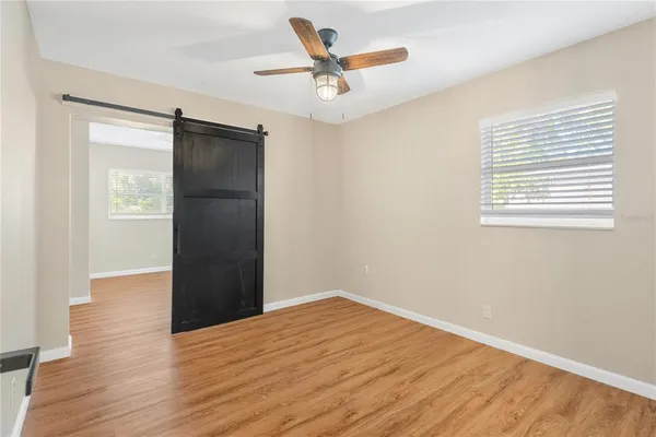 a view of empty room with wooden floor and ceiling fan