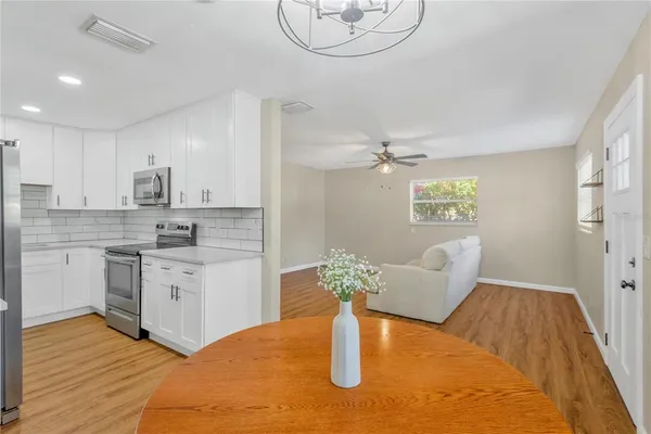 a kitchen with stainless steel appliances granite countertop a sink dishwasher and white cabinets with wooden floor