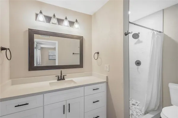 a bathroom with a sink vanity granite toilet and shower