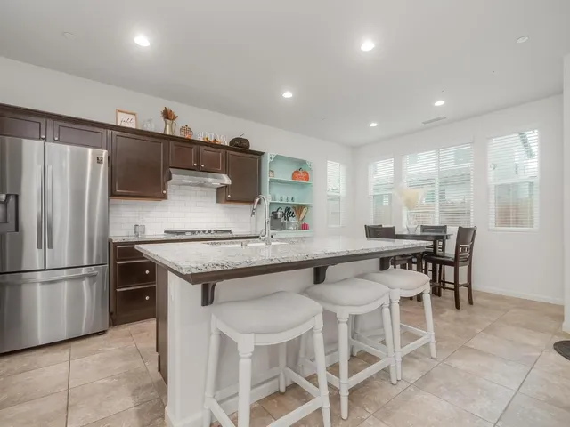 a kitchen with stainless steel appliances granite countertop table chairs stove and refrigerator