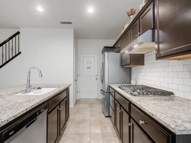 a kitchen with stainless steel appliances granite countertop a sink stove and cabinets