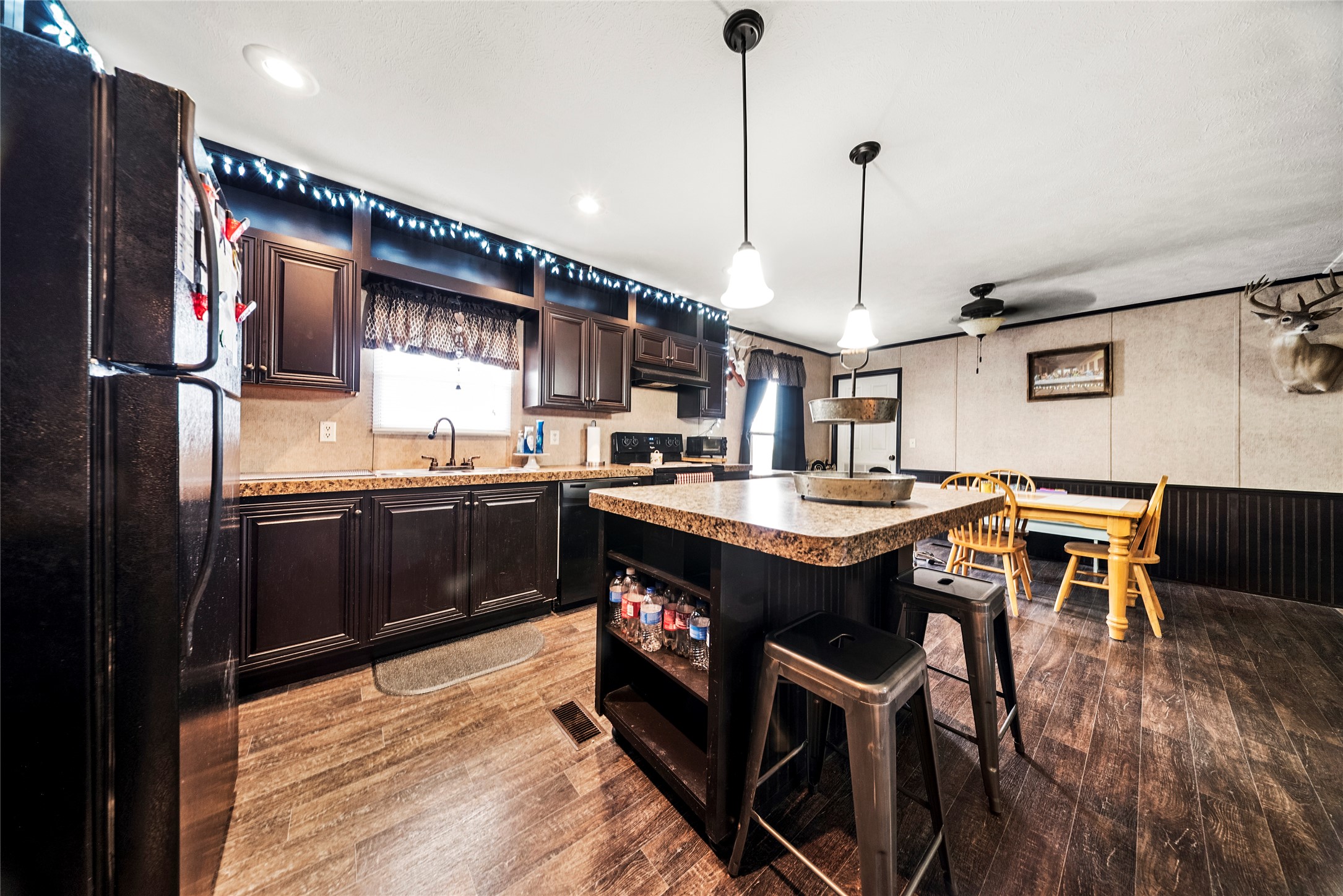 5101 County Road 463 Elgin, TX 78621 - Photo 23 of 38 Kitchen featuring a kitchen bar, black appliances, a center island, decorative light fixtures, and dark wood style floors.