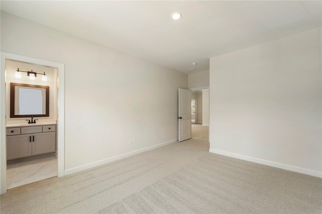114 Lakeside Drive Anderson, SC 29621 - Photo 27 of 37 This spacious primary bedroom features soft carpet flooring, leading to a connected bathroom with modern fixtures.