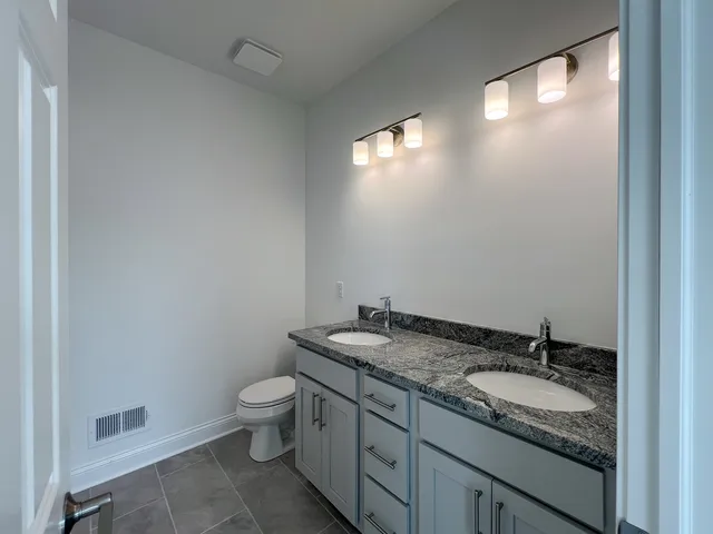 a bathroom with a granite countertop sink a toilet and a mirror
