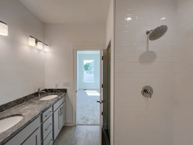 a bathroom with a granite countertop sink a mirror and shower
