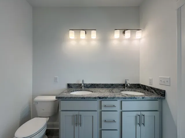 a bathroom with a granite countertop sink and a toilet