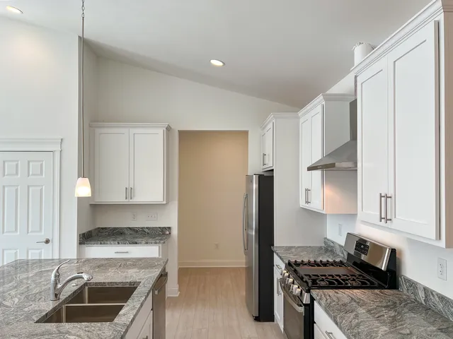 a kitchen with granite countertop a sink stove and refrigerator