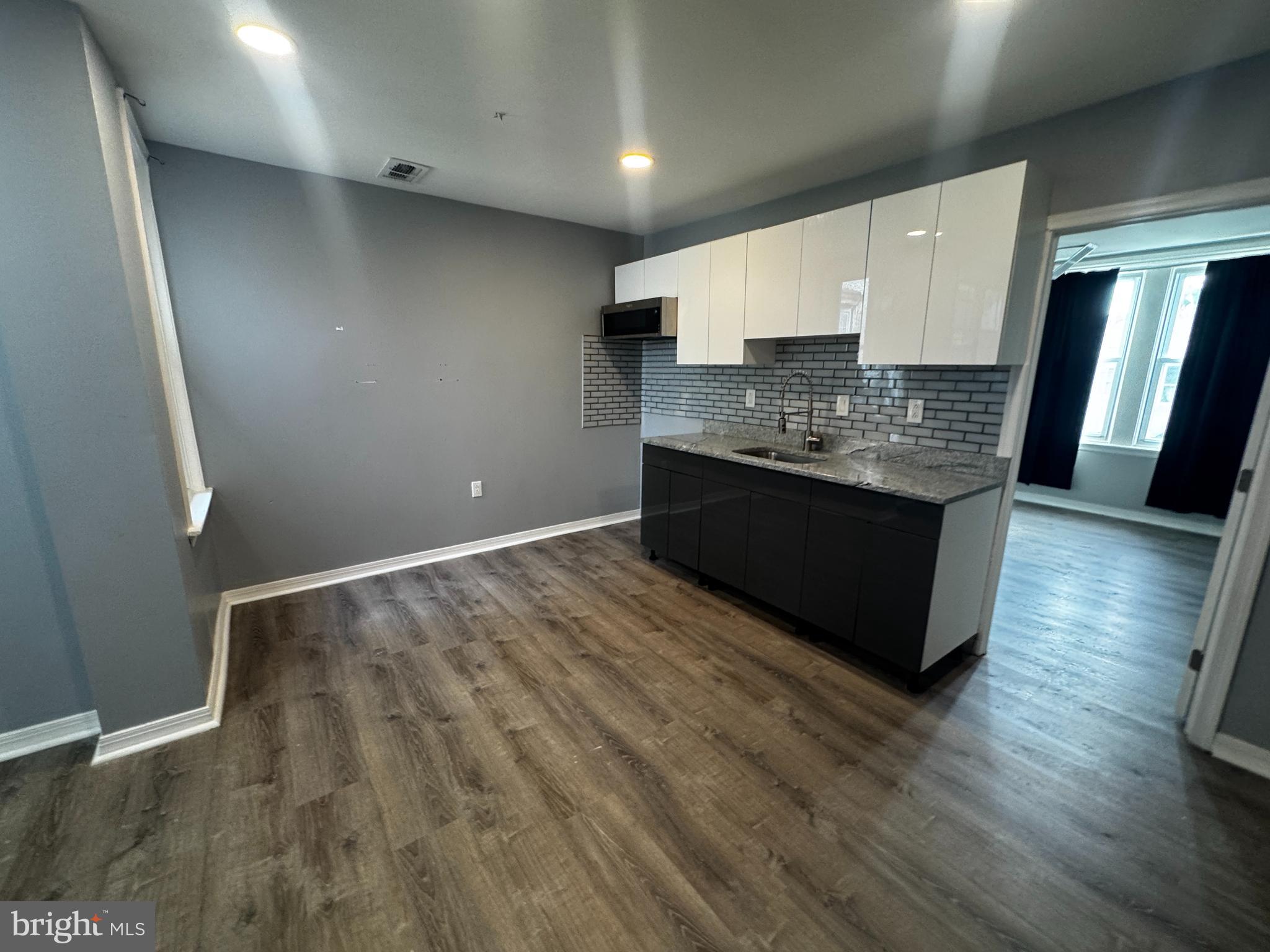 700 Lloyd Street Chester, PA 19013 - Photo 28 of 32 an empty room with wooden floor and kitchen view