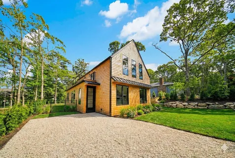 a view of a white house next to a yard with big trees