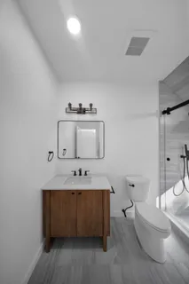 a view of a hallway with wooden floor and a bathroom