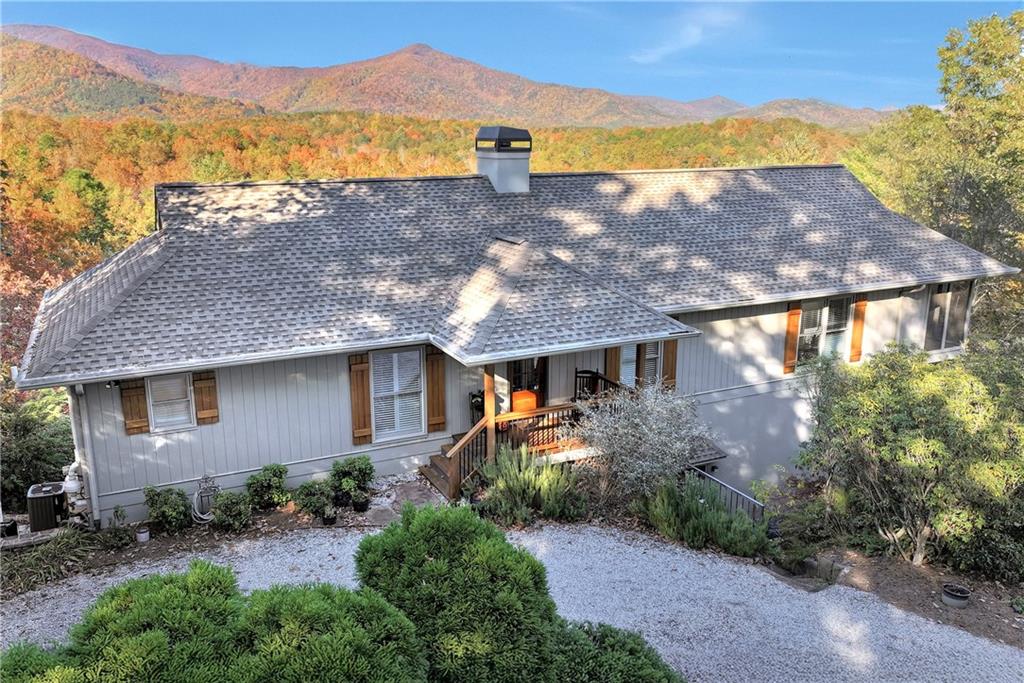 a front view of house with a yard and mountain view in back