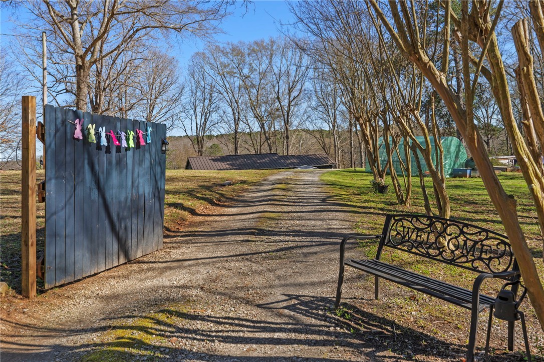 122 Latham Drive Anderson, SC 29621 - Photo 26 of 39 A welcoming gravel driveway leads to a property featuring a sturdy wooden gate and expansive grounds.