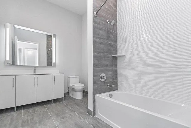 a bathroom with a white bath tub a mirror and a toilet