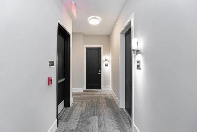 a view of a hallway with wooden floor and cabinets