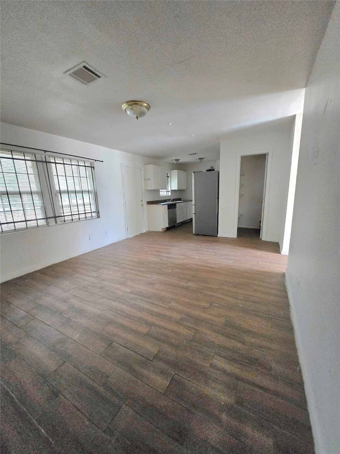 5530 Elm Spring Drive Houston, TX 77048 - Photo 8 of 15 an empty room with wooden floor and kitchen view