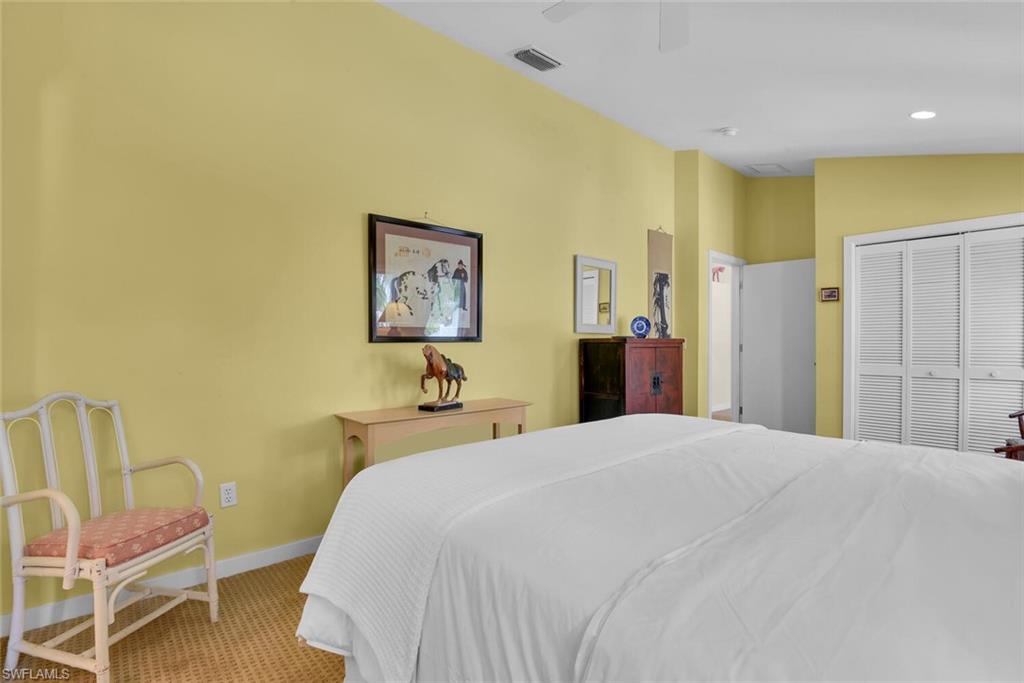 223 11th Avenue South Naples, FL 34102 - Photo 29 of 42 a spacious bedroom with a bed and a chair