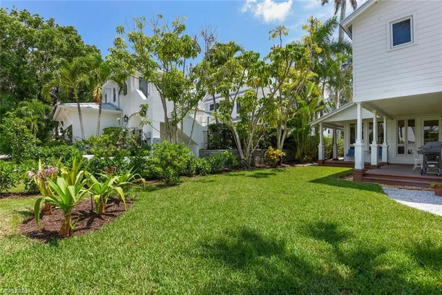 a view of a patio with table and chairs potted plants and large tree