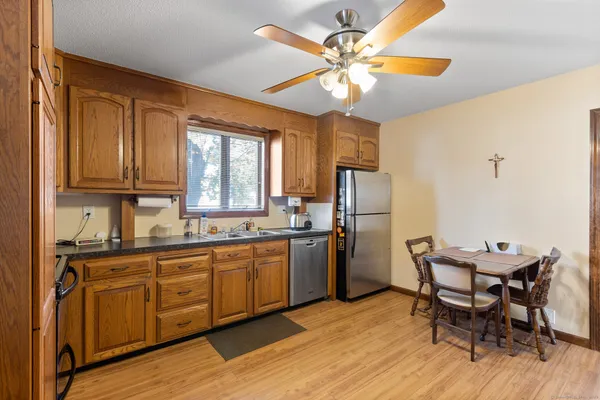 a kitchen with stainless steel appliances granite countertop a dining table chairs refrigerator and sink