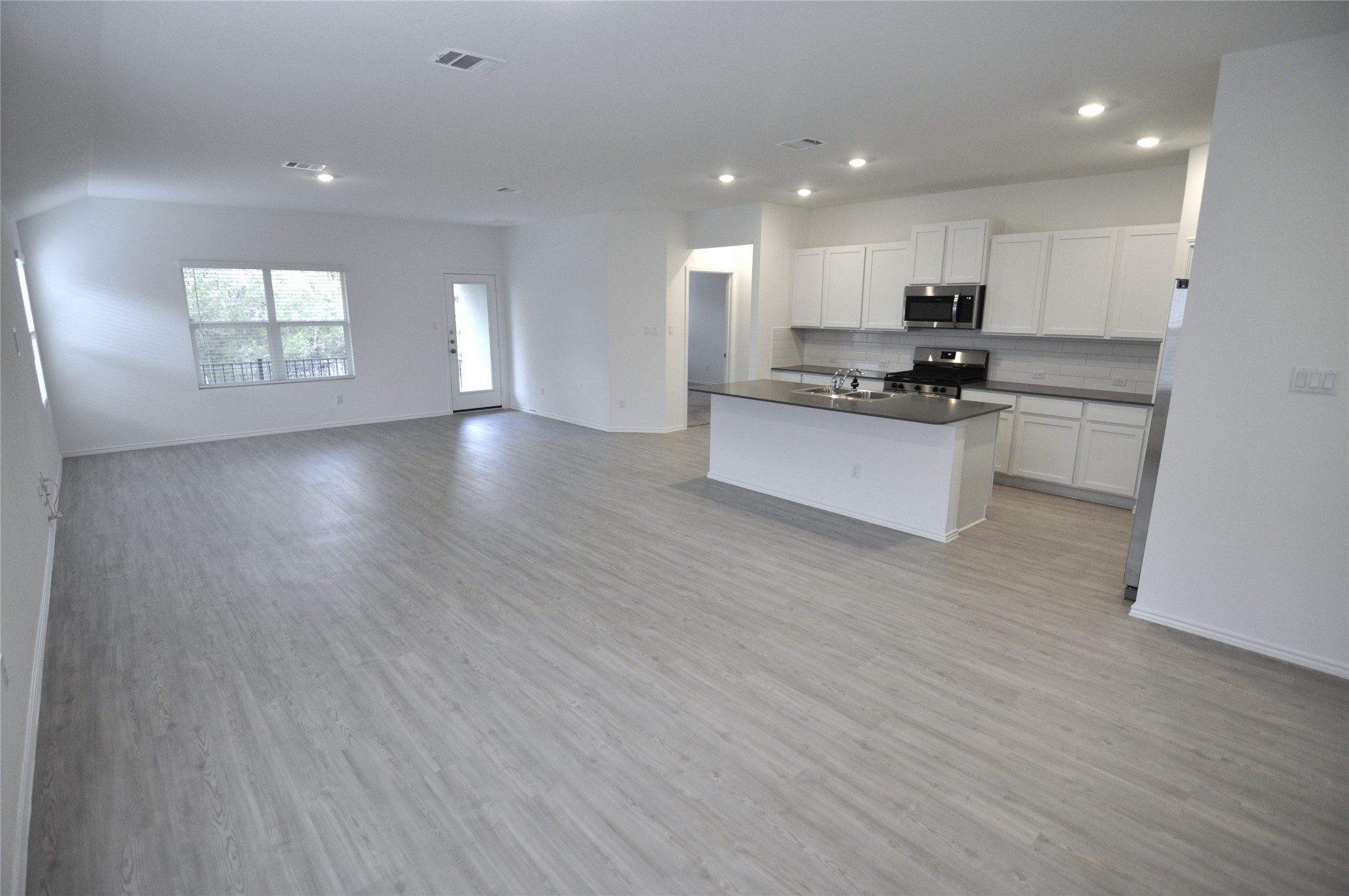 1537 Chapel Ranch Road Georgetown, TX 78628 - Photo 24 of 25 Kitchen with dark countertops, open floor plan, an island with sink, white cabinets, and stainless steel appliances