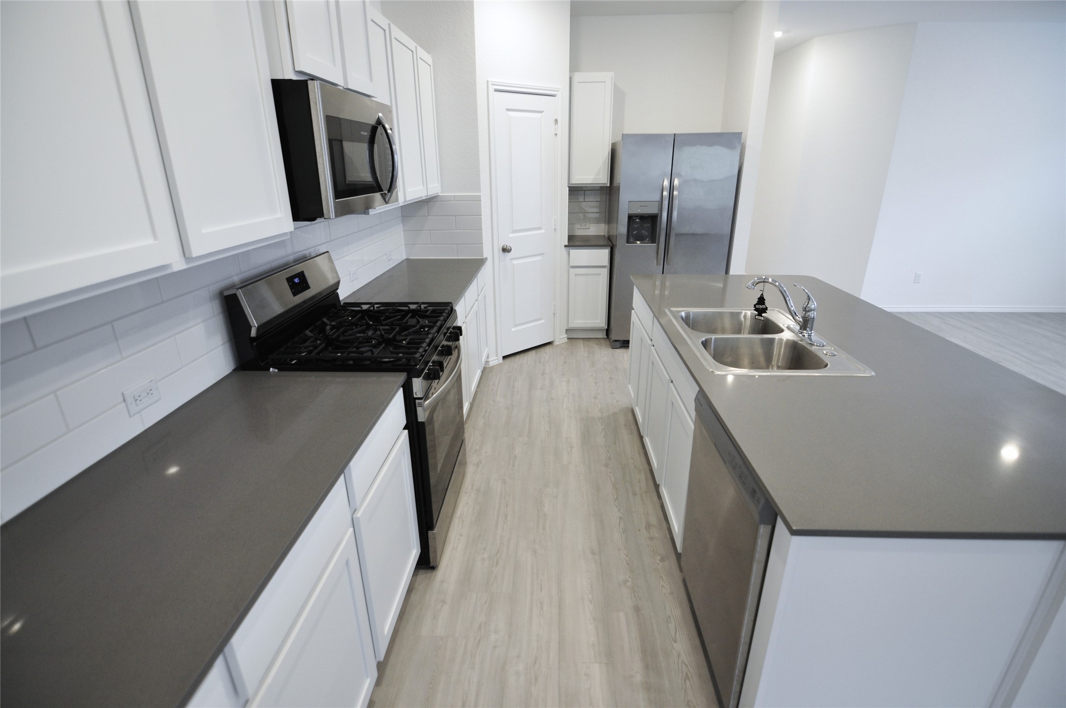 1537 Chapel Ranch Road Georgetown, TX 78628 - Photo 15 of 25 Kitchen with stainless steel appliances, decorative backsplash, light wood finished floors, a center island with sink, and white cabinets
