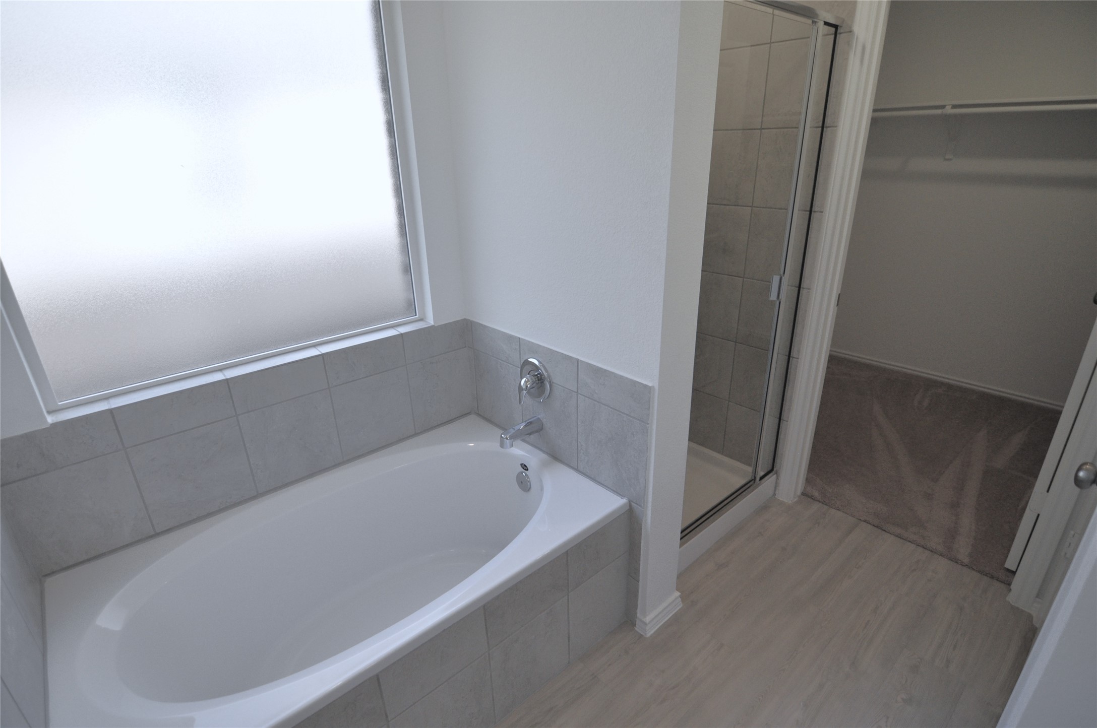 1537 Chapel Ranch Road Georgetown, TX 78628 - Photo 18 of 25 Bathroom with a garden tub, a stall shower, a spacious closet, and light wood-type flooring