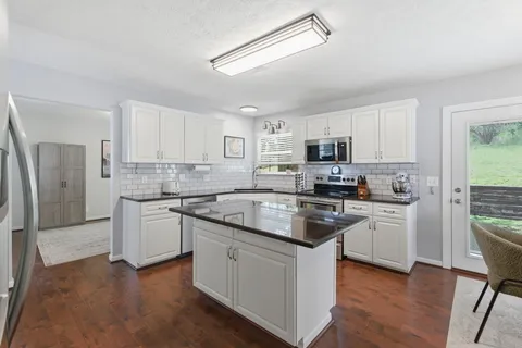 a kitchen with granite countertop white cabinets and stainless steel appliances