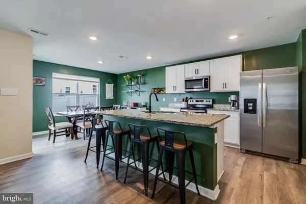 a kitchen with stainless steel appliances granite countertop a table chairs refrigerator and a sink