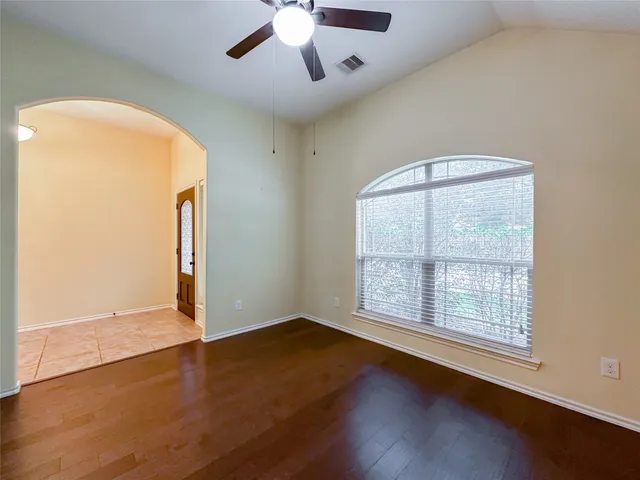 a view of an empty room with window and wooden floor