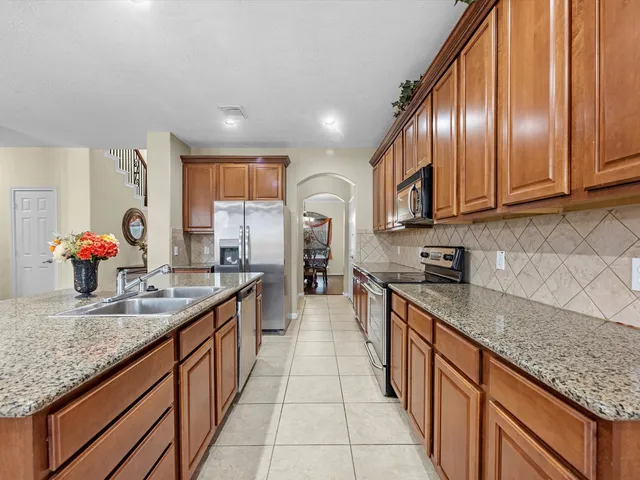 a large kitchen with granite countertop stainless steel appliances a sink stove top oven and cabinets