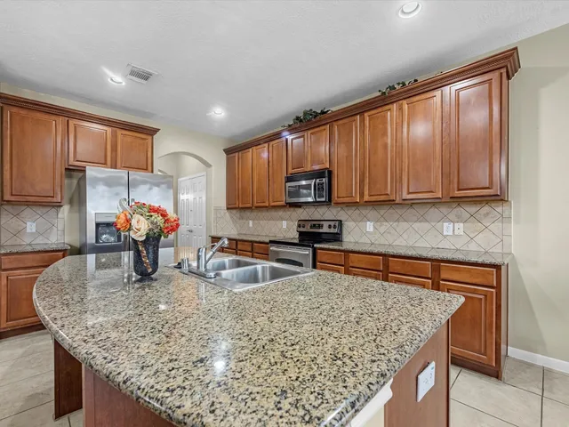 a kitchen with stainless steel appliances granite countertop a sink a microwave and wooden cabinets