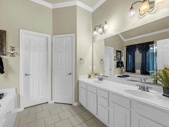 a spacious bathroom with a double vanity sink a mirror a lamp and a bathtub
