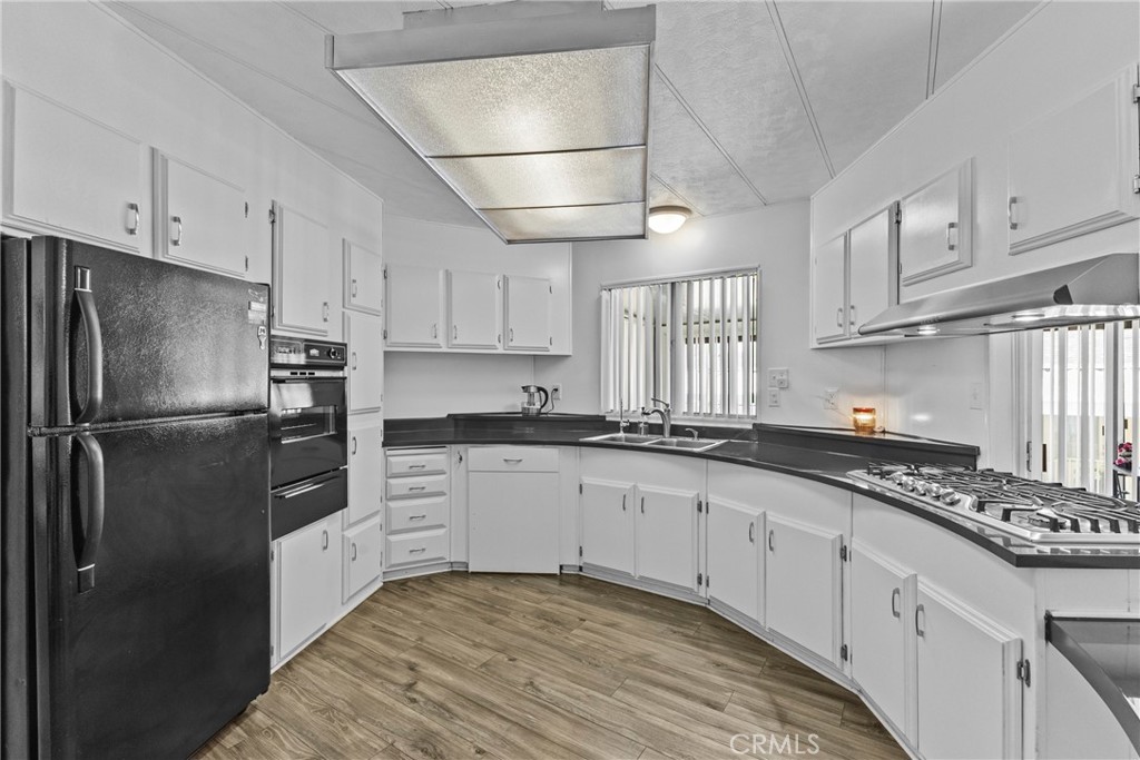 4000 Pierce Street, Unit 132 Riverside, CA 92505 - Photo 14 of 43 a kitchen with granite countertop a refrigerator a sink dishwasher a stove and white cabinets