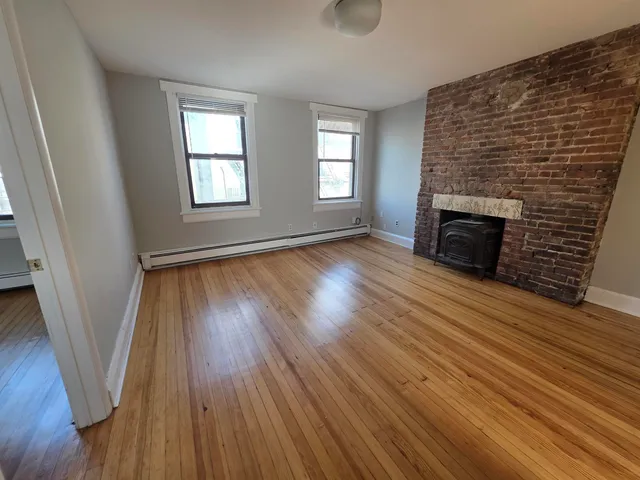 an empty room with wooden floor and fireplace