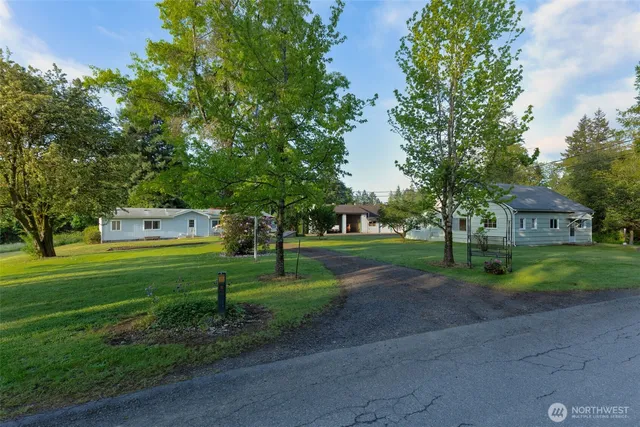 a view of a house with a big yard and large trees