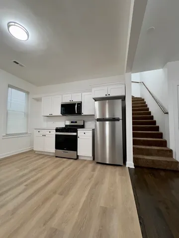 a view of a kitchen with wooden floor and electronic appliances