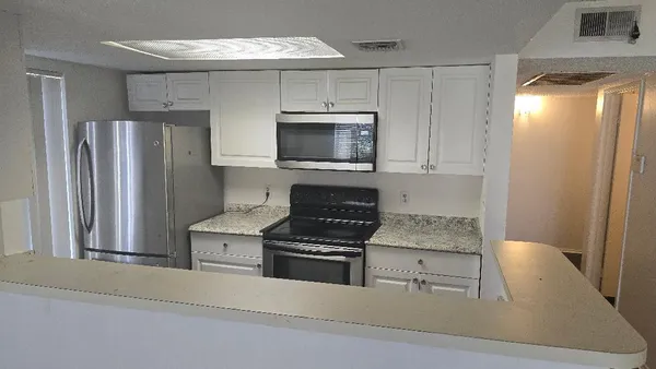 a kitchen with granite countertop a refrigerator stove and microwave