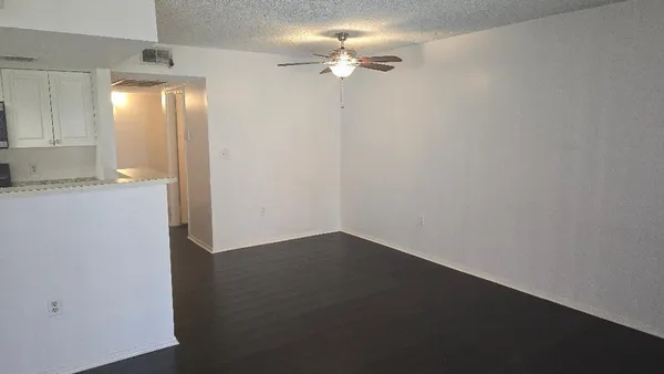 an empty room with a chandelier fan and windows