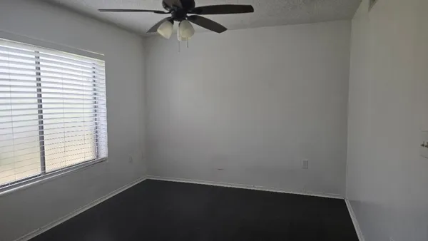 an empty room with a window and a fan