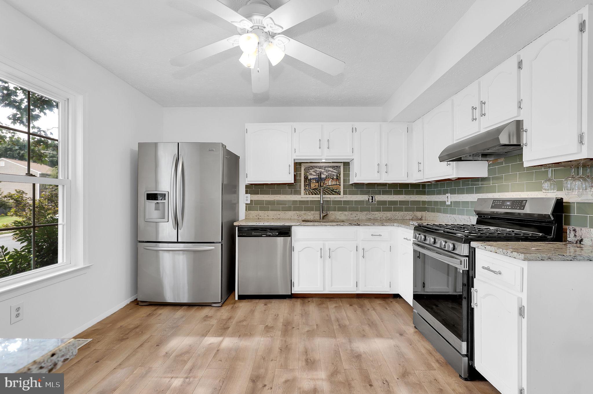 7922 Red Barn Way Elkridge, MD 21075 - Photo 2 of 31 a kitchen with granite countertop a refrigerator a sink a stove and white cabinets