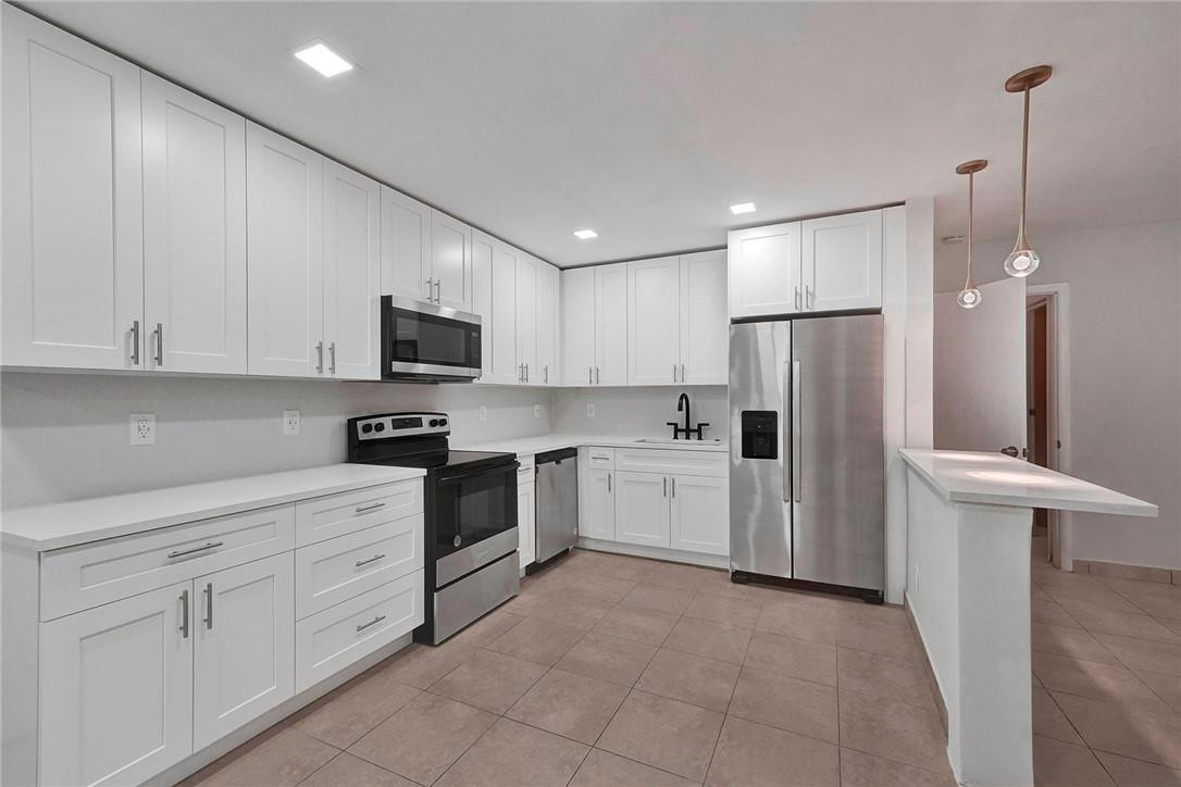313 Southwest 9th Terrace Hallandale Beach, FL 33009 - Photo 5 of 20 a kitchen with white cabinets and stainless steel appliances