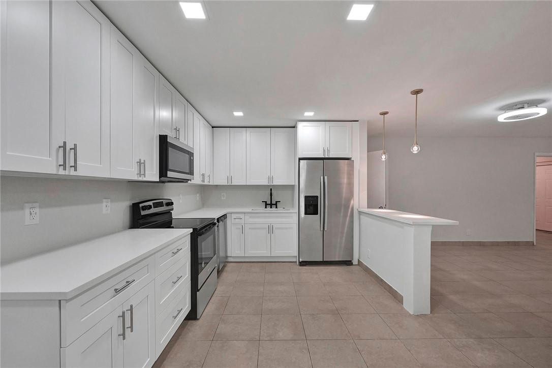 313 Southwest 9th Terrace Hallandale Beach, FL 33009 - Photo 6 of 20 a kitchen with cabinets and white appliances