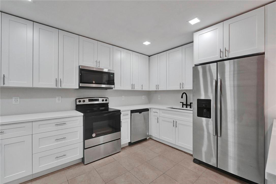 313 Southwest 9th Terrace Hallandale Beach, FL 33009 - Photo 7 of 20 a kitchen with white cabinets and stainless steel appliances