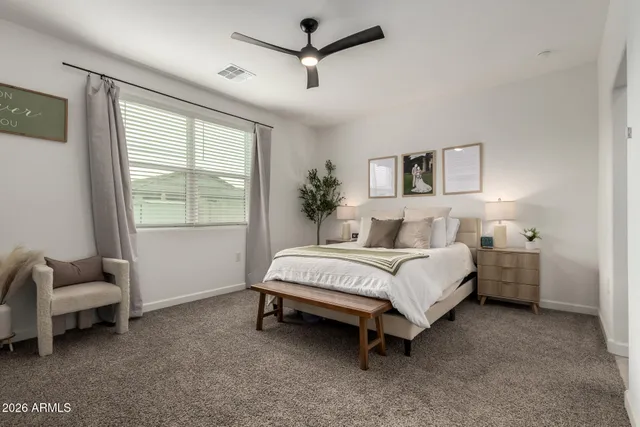 a bed sitting in a bedroom next to a window and a chair