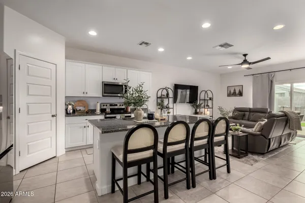 a kitchen with granite countertop a table chairs stove and microwave