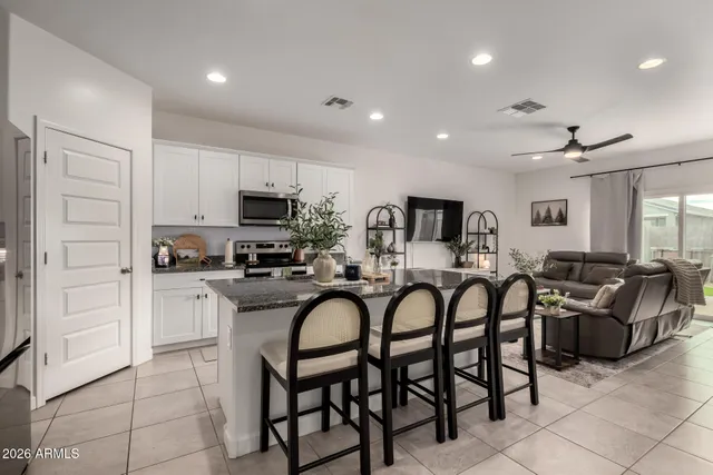 a kitchen with granite countertop a table chairs stove and microwave