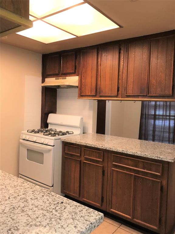 a kitchen with granite countertop wooden cabinets and a stove top oven