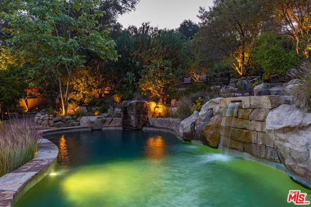 a view of a lake with lawn chairs and a large tree