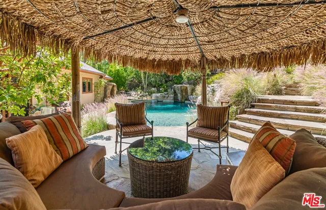 a view of a patio with couches table and chairs potted plants and large tree