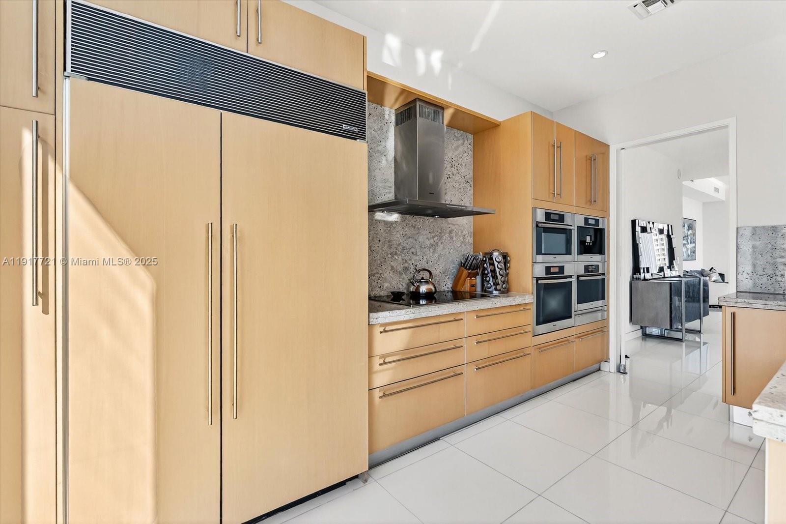 900 Brickell Key Boulevard, Unit 2304 Miami, FL 33131 - Photo 17 of 55 a large white kitchen with stainless steel appliances kitchen island granite countertop a refrigerator and cabinets